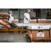 Un opérateur scanne un code barre sur un carton de produits alimentaires dans un entrepôt de préparation de commandes.