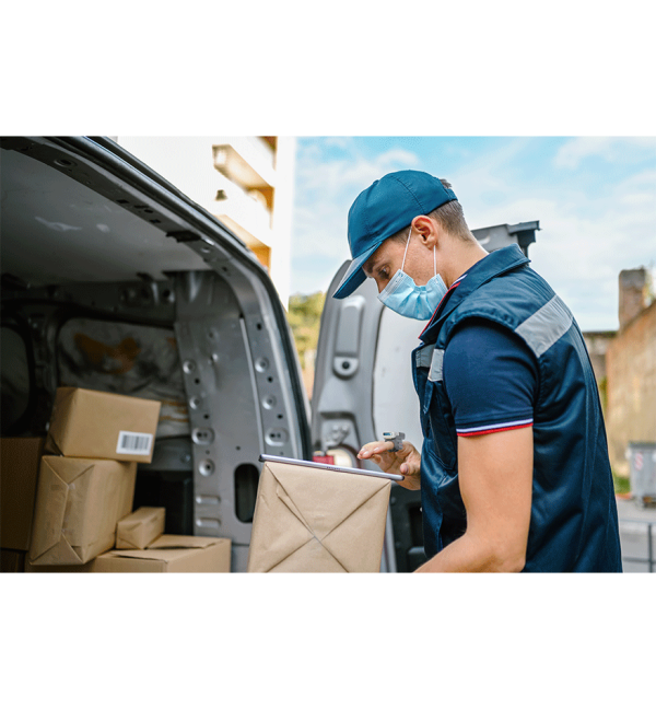 un livreur devant un camion de livraison scanne un code barre sur un carton avec une bague honeywell 8675i scanner mains-libres