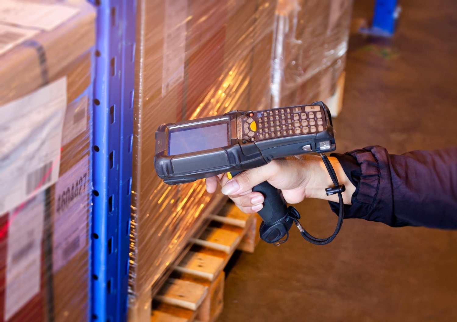 photo d'un terminal dans une main dans un entrepot qui scan un carton