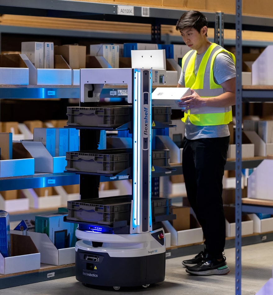 Robot AMR Zebra Flex en entrepôt. Employé manipulant un colis près du robot.