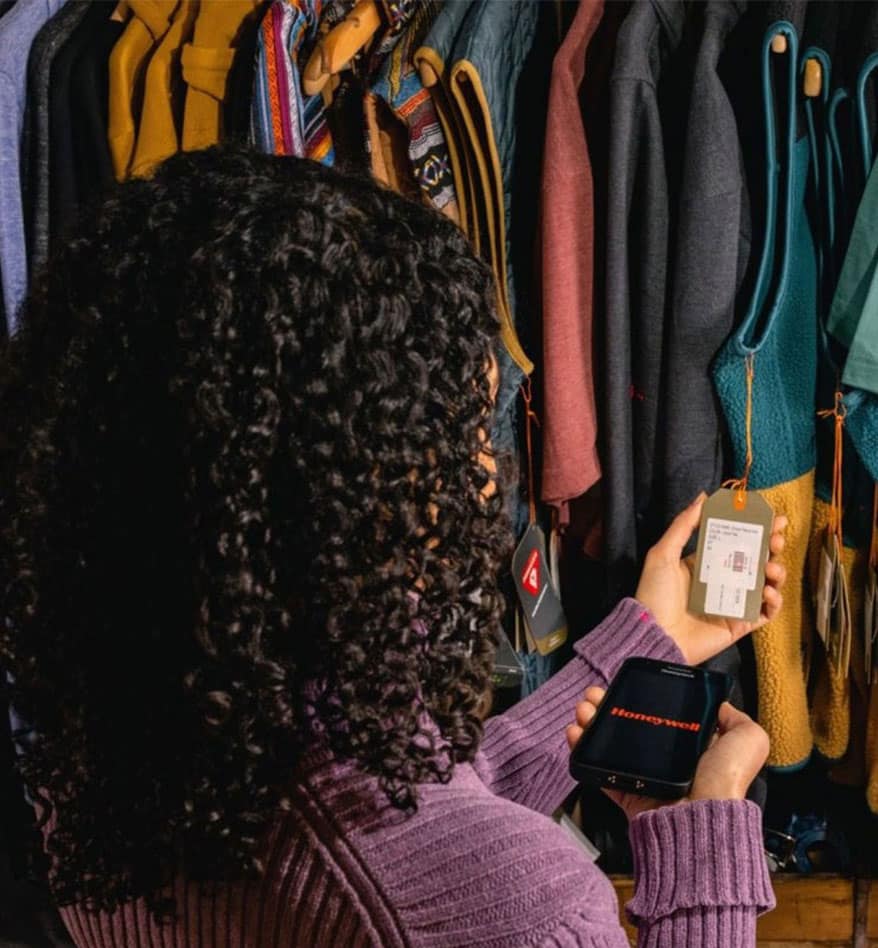 Femme utilisant un terminal mobile durci CT30XP Honeywell pour scanner une étiquette de vêtement.