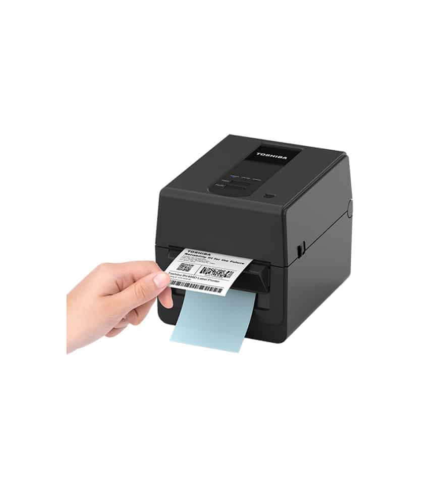 Imprimante de bureau Toshiba BV420D imprimant une étiquette. Main tenant l'étiquette imprimée.
