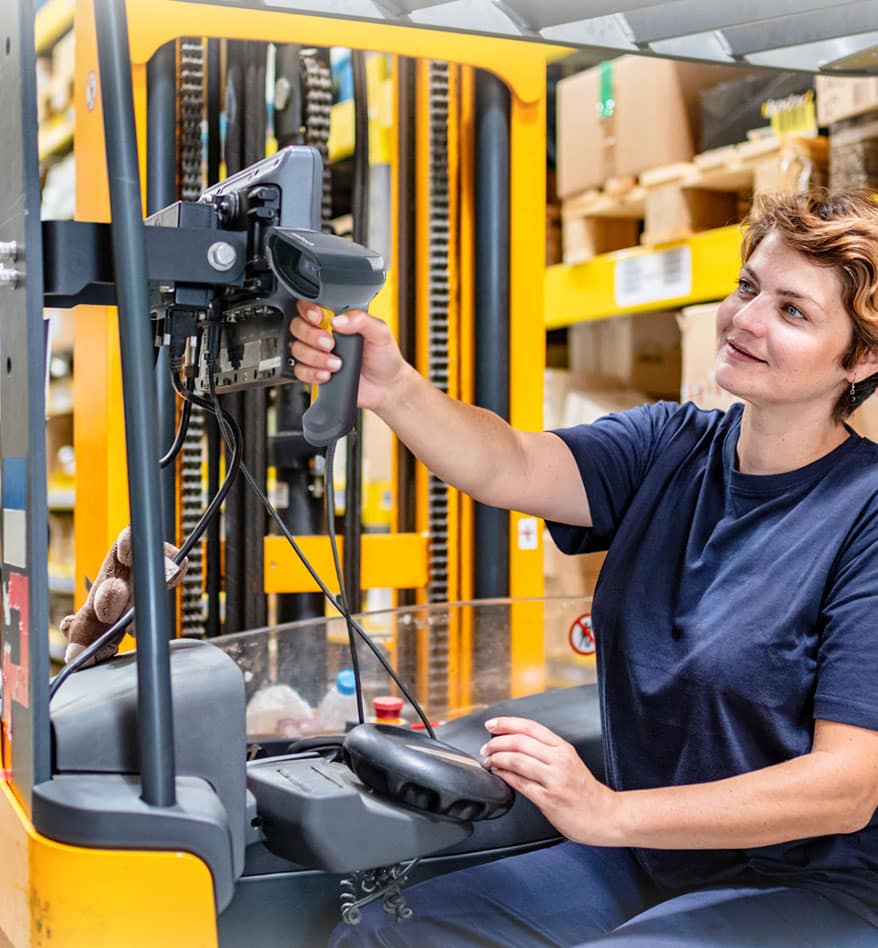 Opératrice de chariot élévateur utilisant le scanner Unitech MS852LR dans un entrepôt.