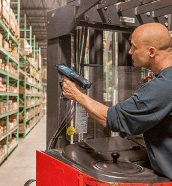 Un homme utilisant un terminal MC9300 Zebra dans un entrepôt.