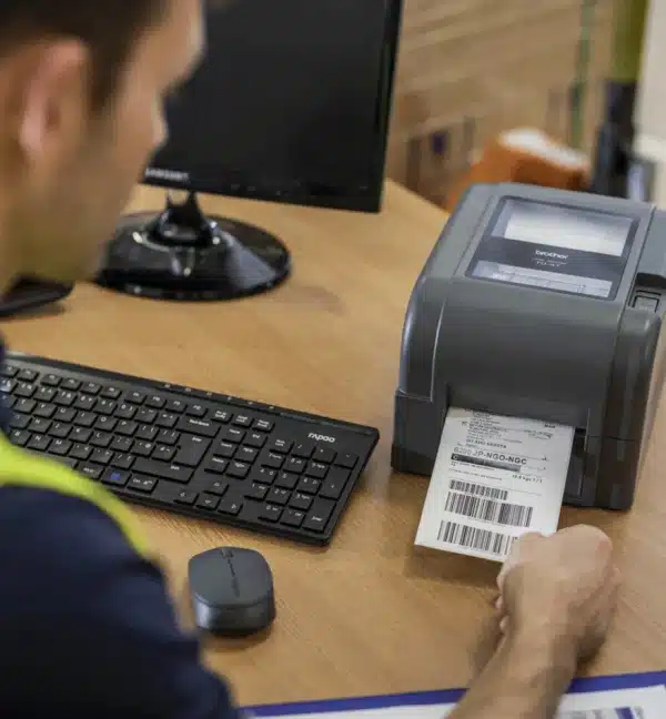 Homme utilisant une imprimante de bureau Brother TD4650 pour imprimer une étiquette.