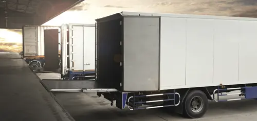 Camions de livraison alignés à un quai de chargement, solutions de gestion de flotte IoT.