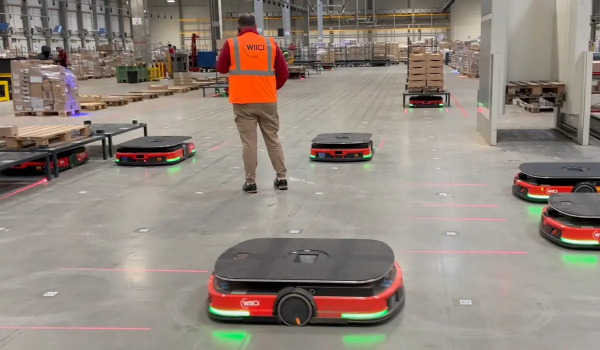 Robots autonomes WIILO dans un entrepôt, supervisés par un employé. Solution logicielle robotique MAEVE.