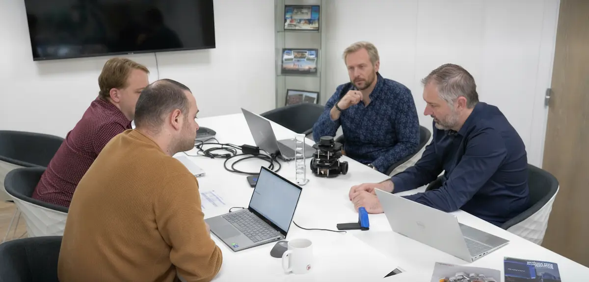 Réunion d'équipe autour d'une table avec un robot AMR "pallet to person".
