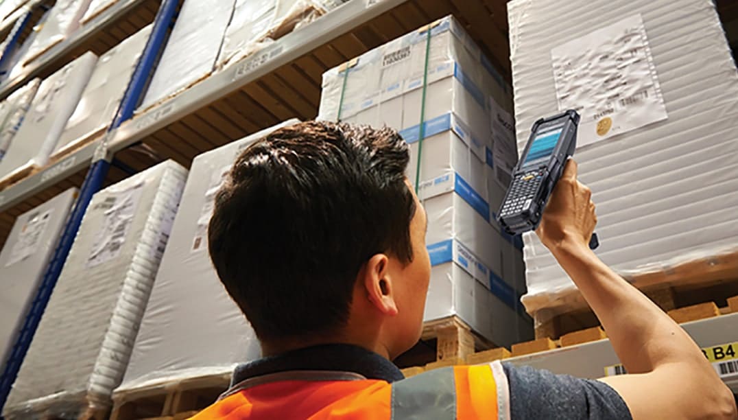 Employé scannant des palettes dans un entrepôt pour la gestion des activités d'entrepôt.