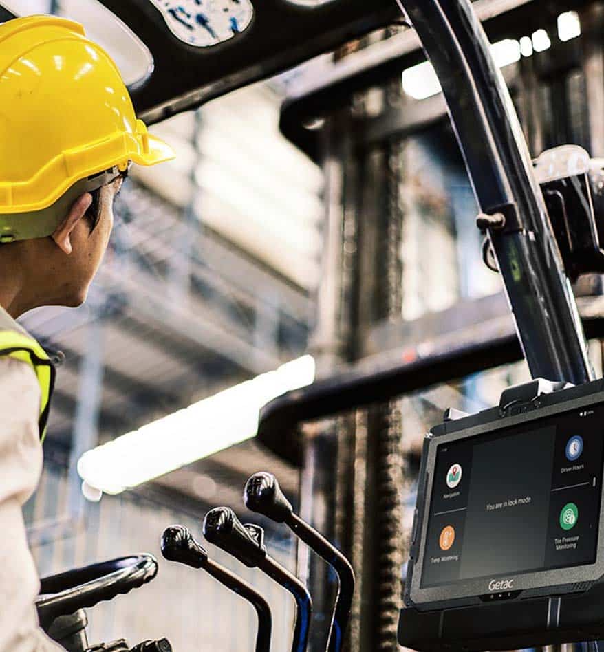 Tablette durcie Getac ZX10 utilisée dans un chariot élévateur, avec opérateur portant un casque jaune.
