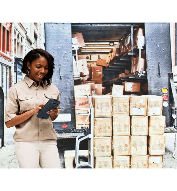 Femme utilisant un Honeywell EDA71 devant un camion de livraison rempli de cartons.