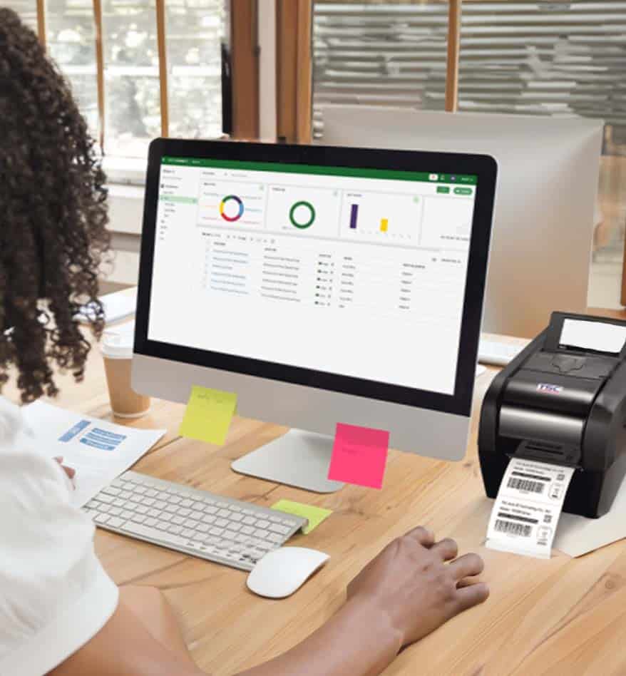 Femme utilisant une imprimante de bureau TSC DA210/220 avec un ordinateur affichant des données.