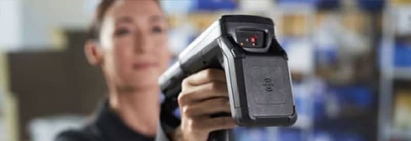 Employée utilisant un scanner de codes-barres pour solutions de gestion d'entrepôt.