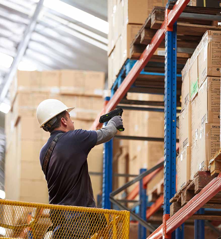 Employé scannant des boîtes avec un terminal industriel Zebra MC3400 dans un entrepôt.