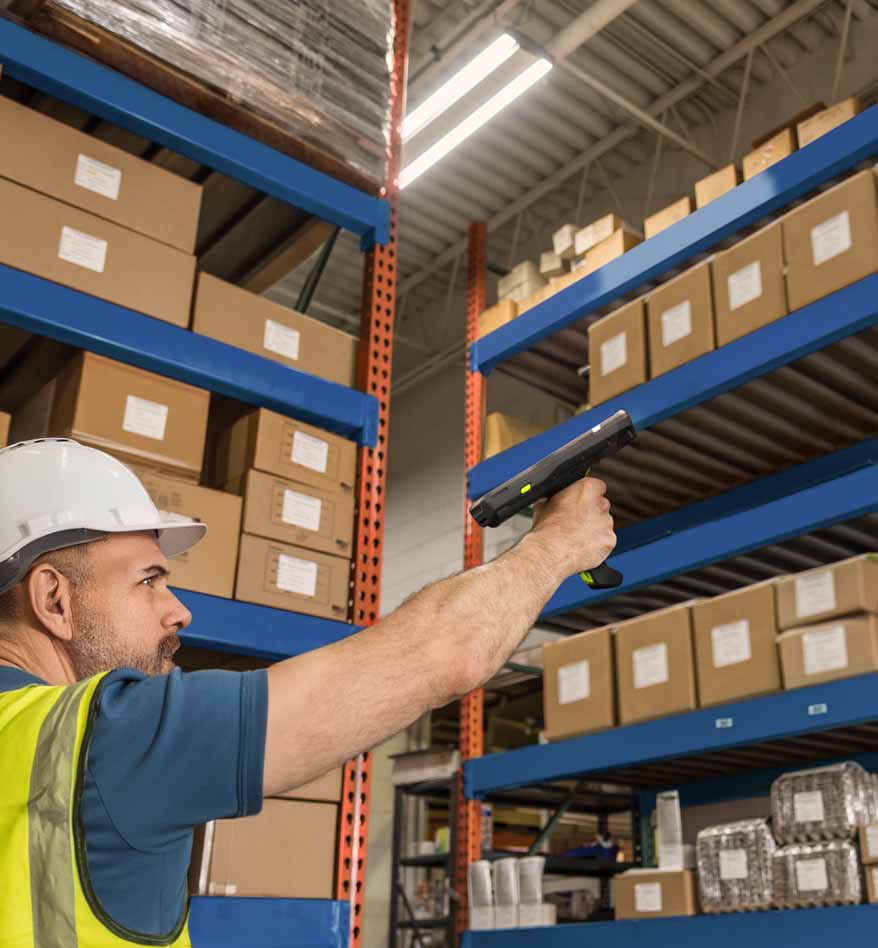 Ouvrier scannant un code-barres avec un terminal industriel Zebra MC3400 dans un entrepôt.