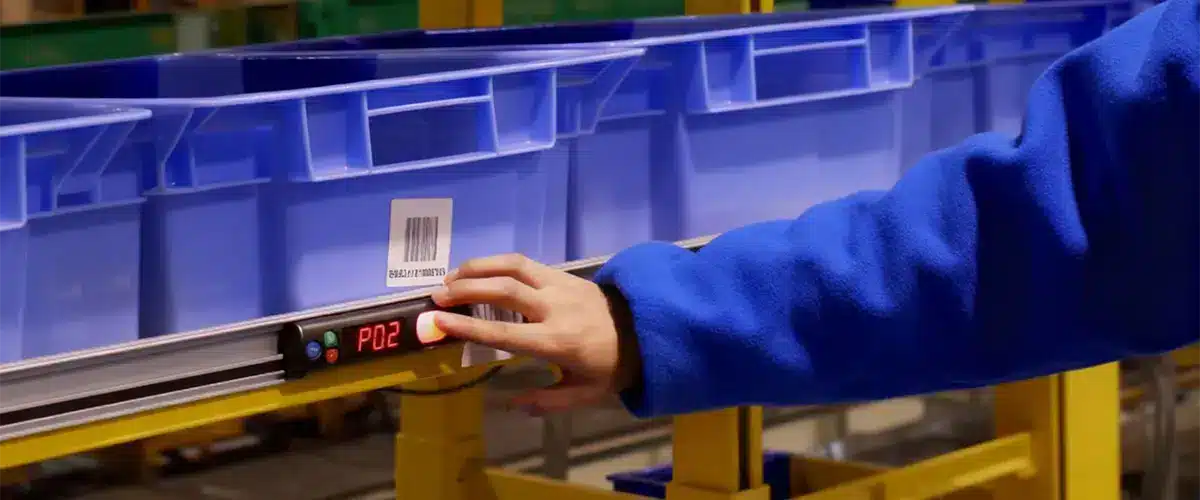 Préparation de commande : caisses bleues avec codes-barres sur convoyeur.