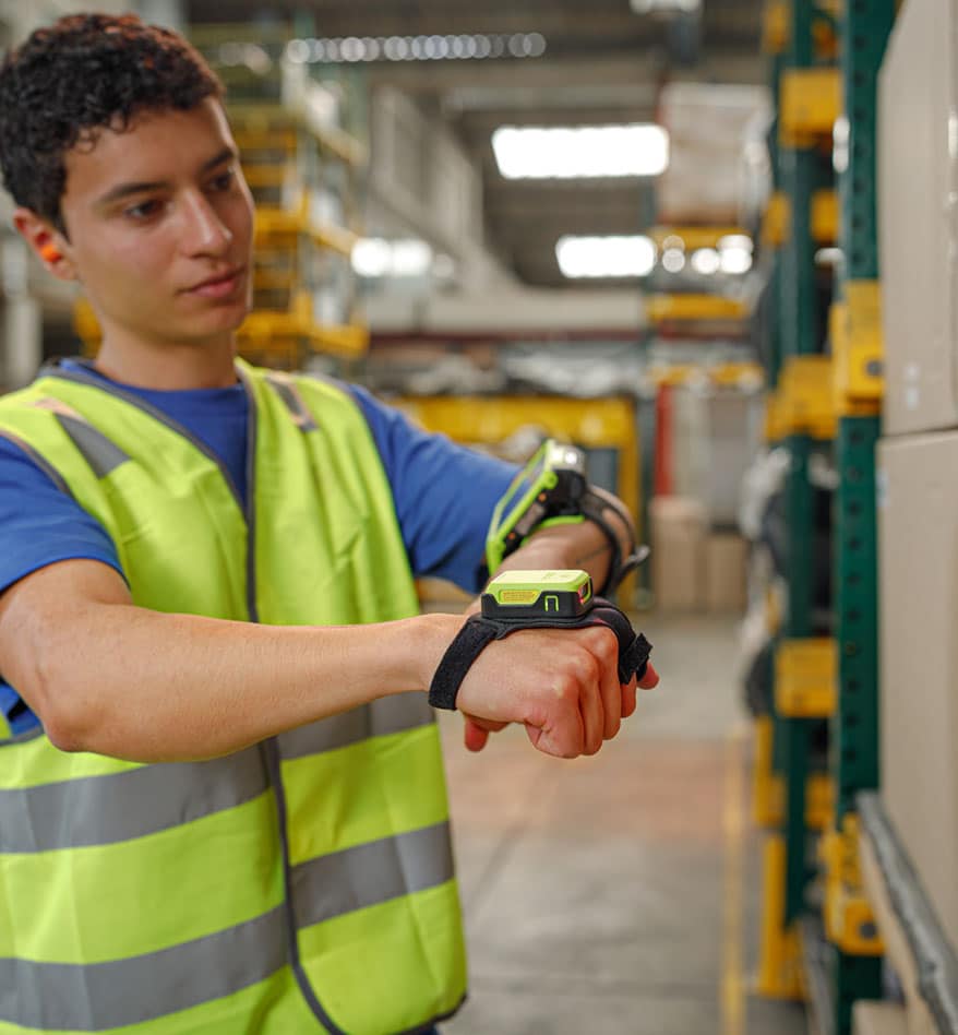 Employé d'entrepôt utilisant un scanner transportable Zebra RS2100 sur son poignet.