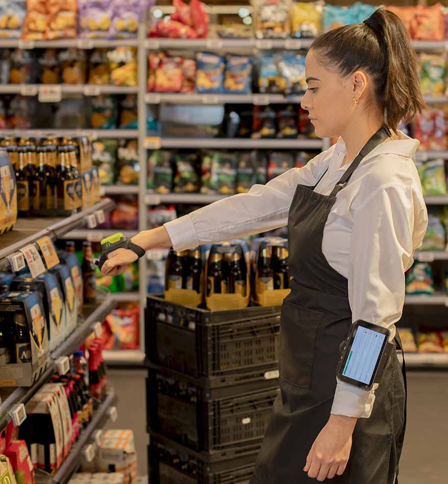 Employée de magasin utilisant un scanner transportable Zebra RS2100 pour vérifier les produits en rayon.