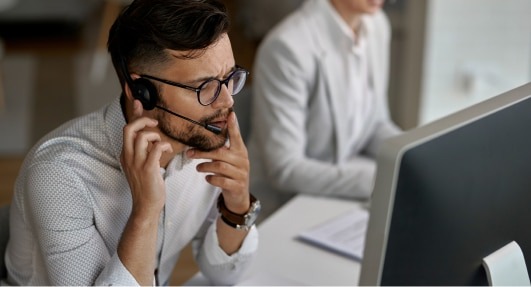 Homme au service clientèle Privilege, portant un casque et regardant un écran d'ordinateur.