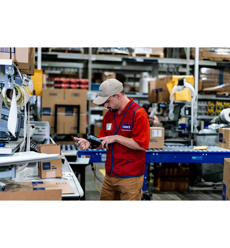 Employé Lowe's utilisant un scanner RS5100 Zebra pour scanner des colis dans un entrepôt.
