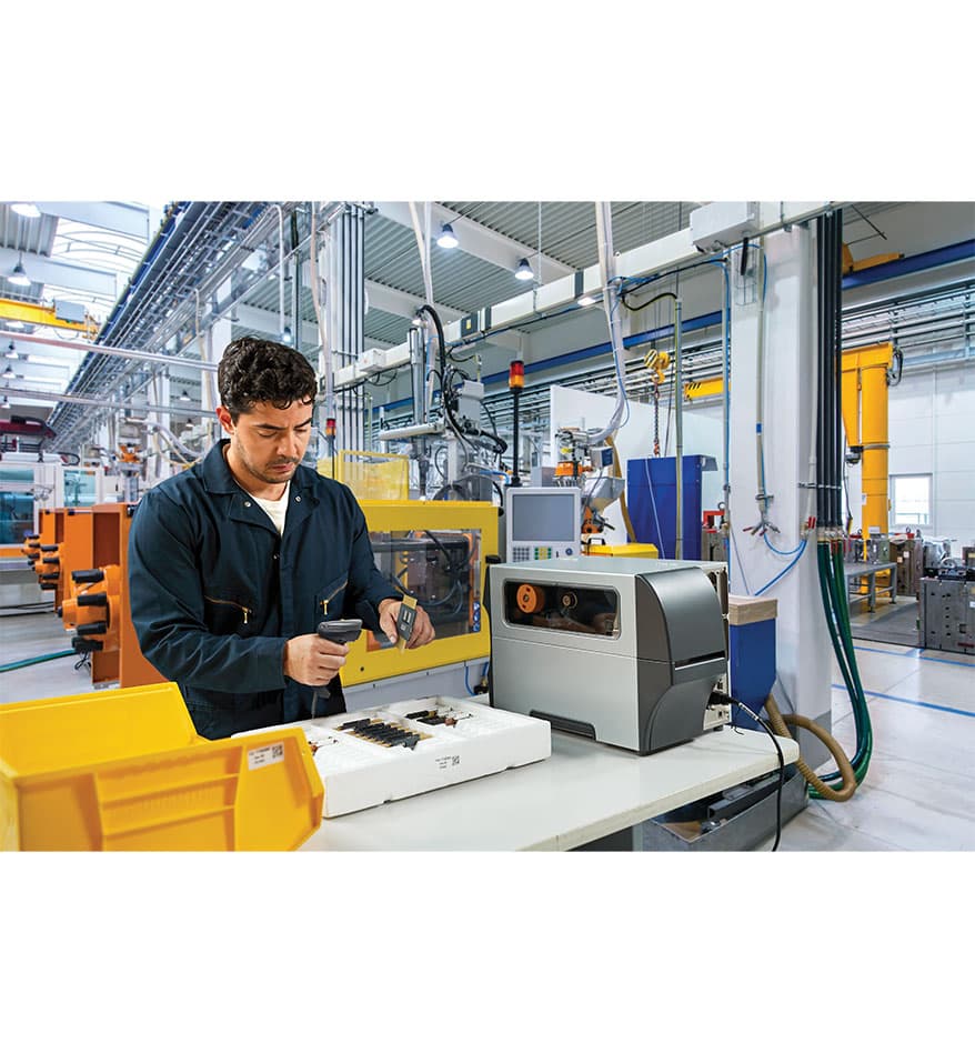 Ouvrier utilisant un scanner Zebra DS4600 dans une usine. Série de Scanners DS4600 Zebra.