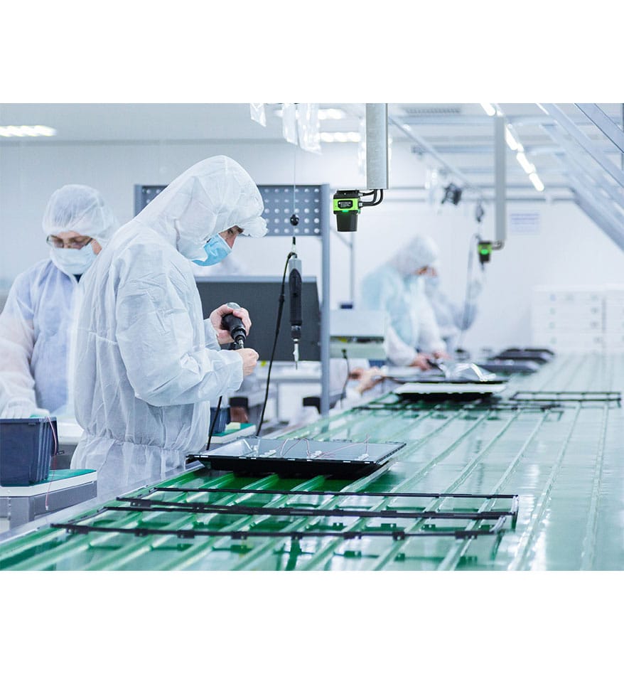 Ouvriers en salle blanche assemblant des écrans avec un Scanner FS70 Zebra.