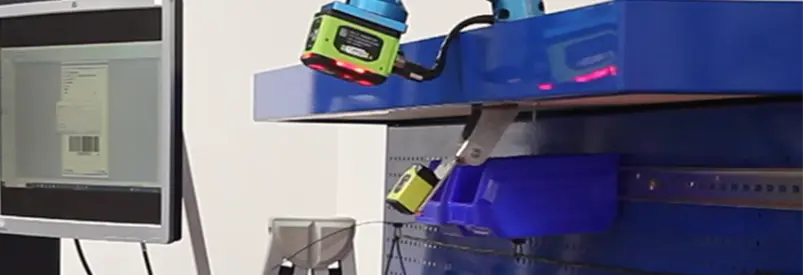 Système de préparation de commande avec scanners et bacs bleus, écran affichant un code-barres.