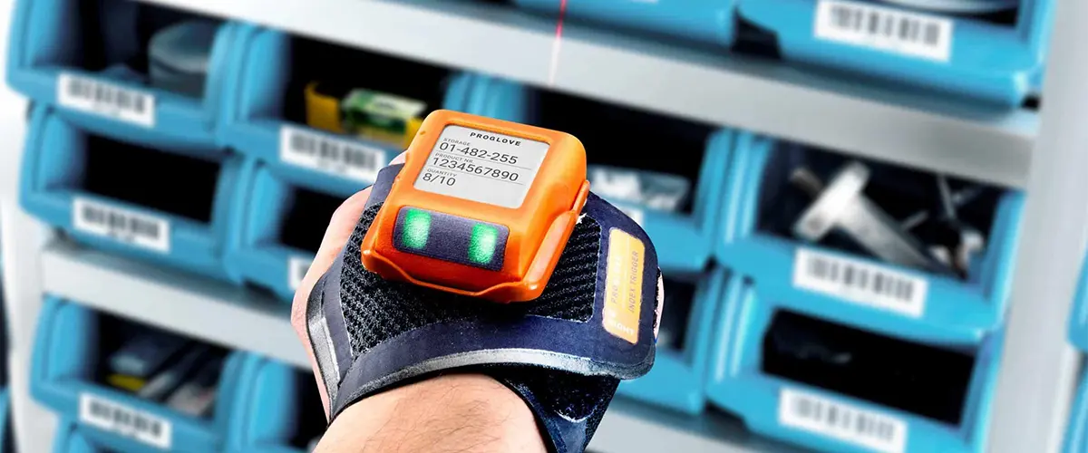 Solutions de préparation de commande : lecteur de codes-barres portable sur un gant, pointant sur un code.