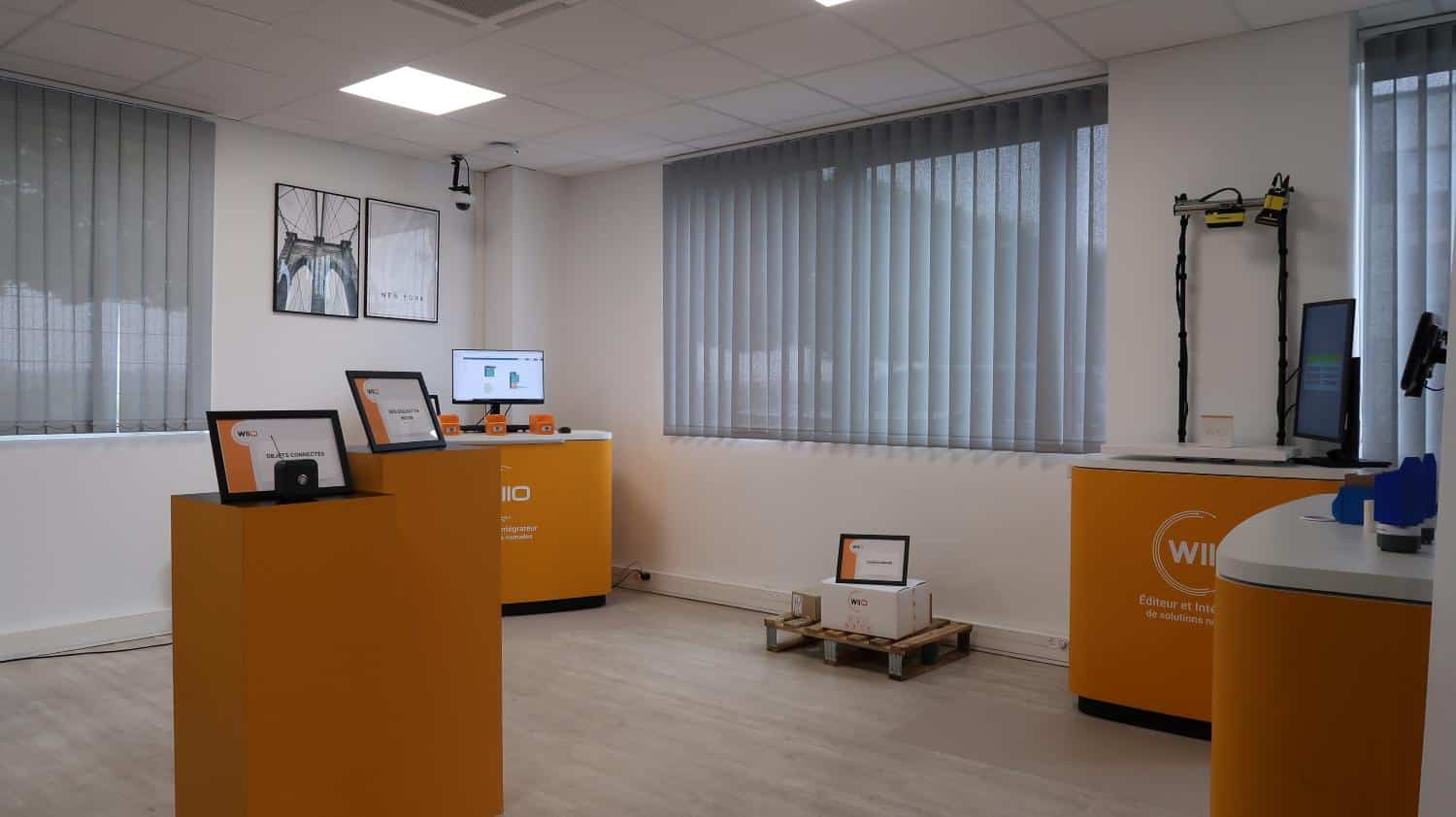 Showroom WIIO avec présentoirs orange et écrans. Éditeur et intégrateur de solutions numériques.