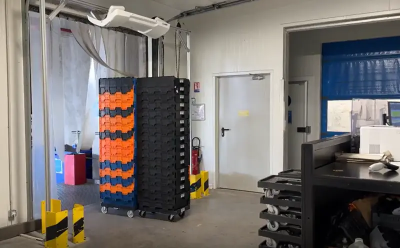 Entrepôt PARISNORDIS avec chariots de bacs orange et noirs, et porte industrielle.