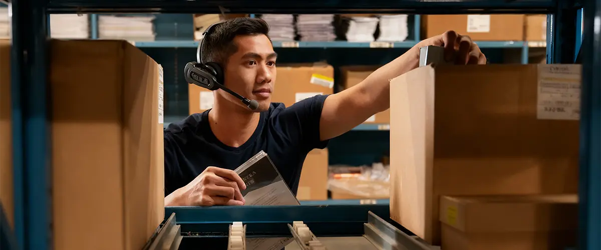Employé d'entrepôt utilisant des solutions de préparation de commande avec un casque.