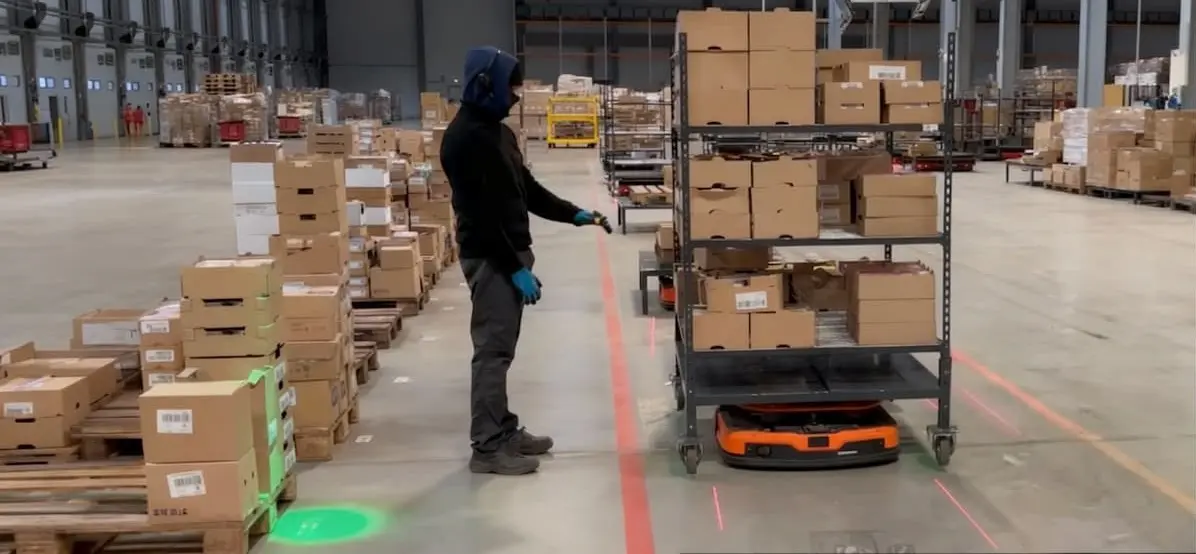 Automatisation des flux d'entrepôt : Employé travaillant avec un robot mobile dans un entrepôt.