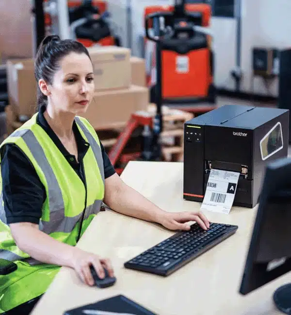 Femme utilisant une imprimante industrielle Brother TJ-4121TN dans un entrepôt.