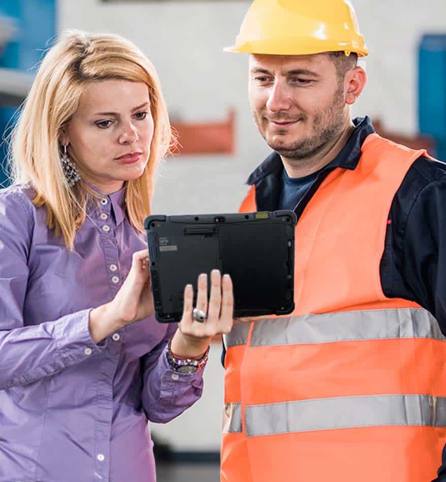 Femme et ouvrier regardant une tablette durcie Honeywell RT10 sur un chantier.