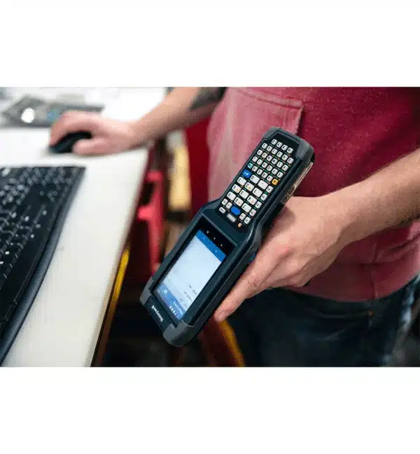 Terminal industriel Honeywell CK65 tenu à la main, clavier et écran visibles.