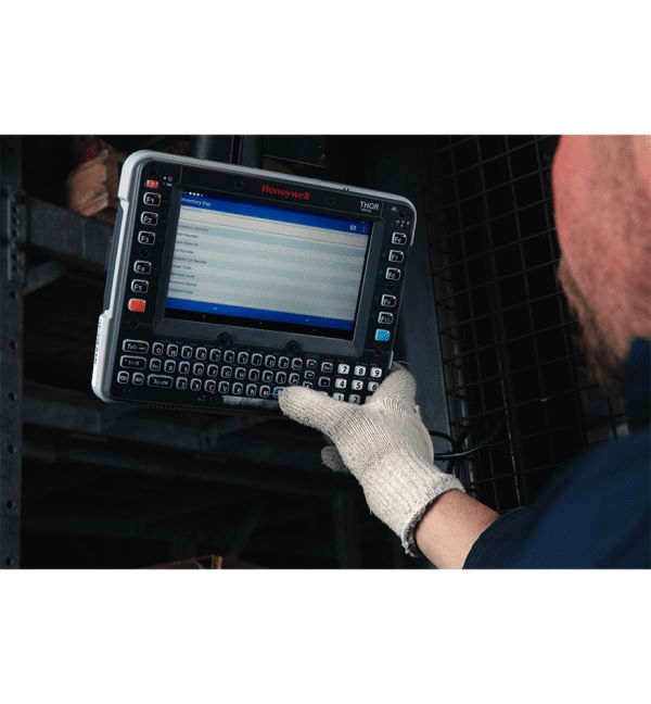 Terminal embarqué Honeywell VM1A utilisé dans un entrepôt par un employé portant des gants.