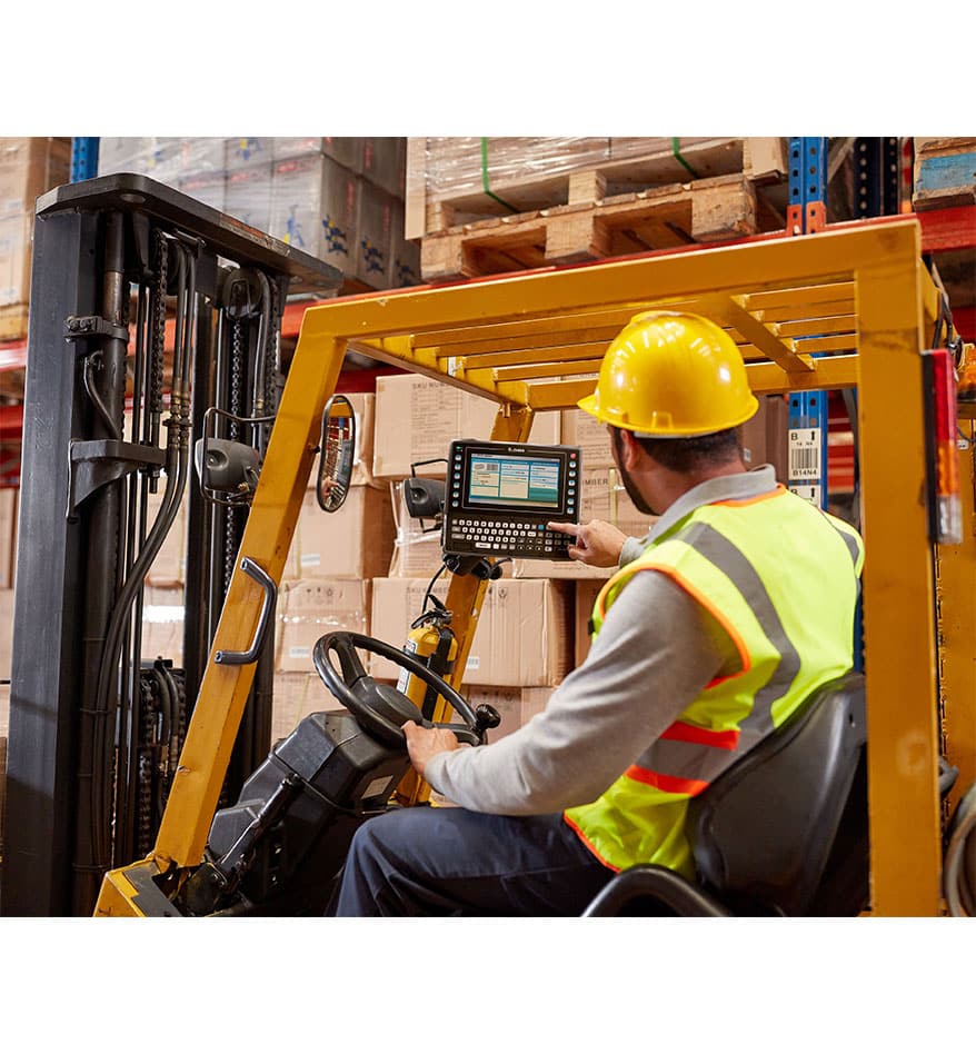 Opérateur sur chariot élévateur utilisant un terminal VC8300 Zebra dans un entrepôt.