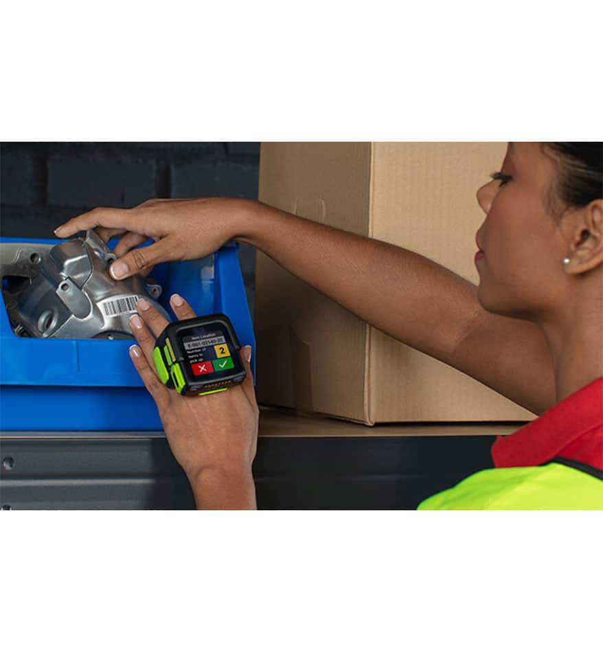 Employée utilisant le terminal mains-libres Zebra WS50 pour scanner un code-barres sur une pièce.