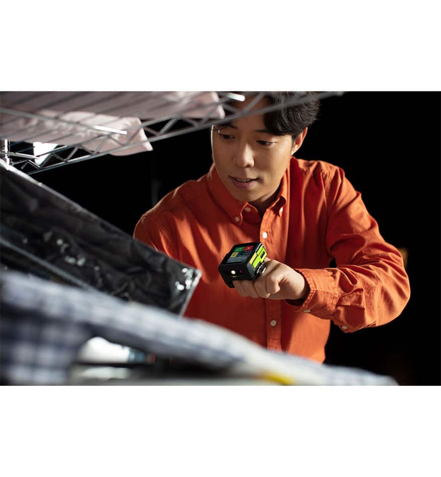 Homme utilisant le terminal mains-libres Zebra WS50 pour scanner des articles dans un entrepôt.