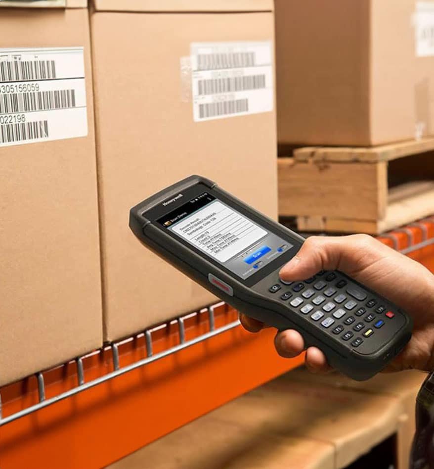 Terminal industriel Honeywell EDA61K en cours de scan de codes-barres sur des cartons.