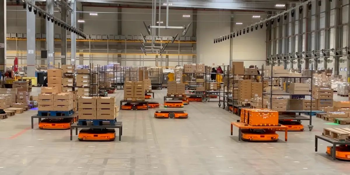 Entrepôt avec robots transportant des marchandises, automatisation des flux de production.