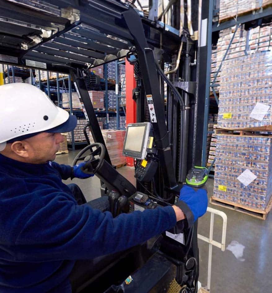 Employé d'entrepôt utilisant un scanner Zebra DS3600-ER sur un chariot élévateur.
