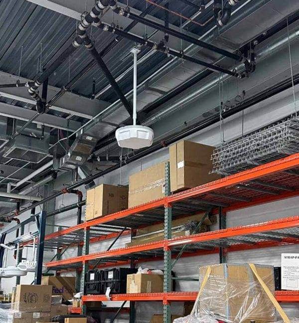 Entrepôt avec étagères et lecteur RFID Zebra ATR7000 suspendu au plafond.