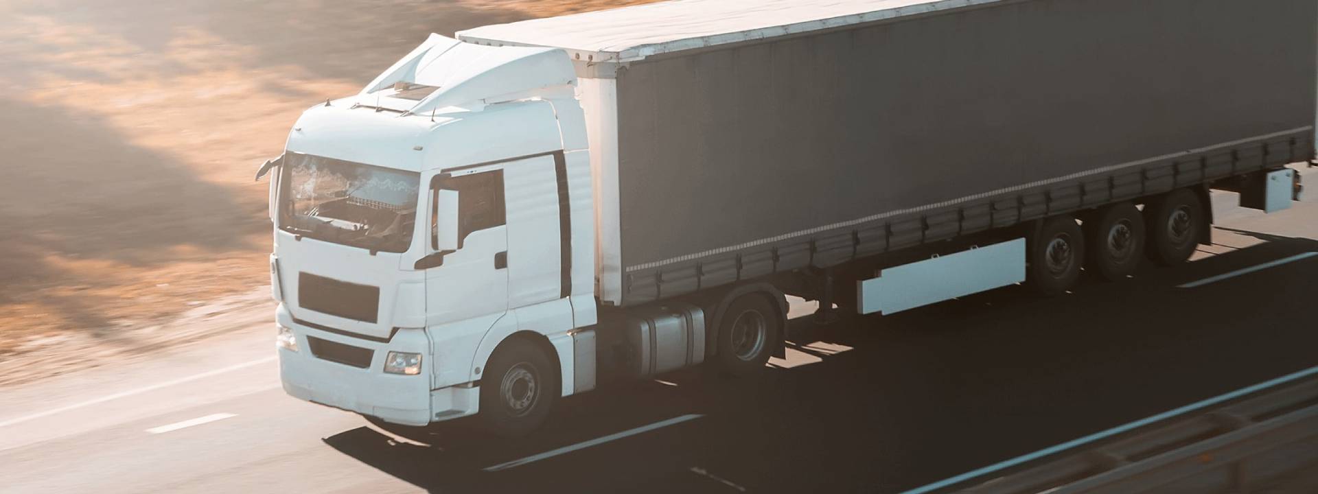 Camion blanc sur autoroute, représentant une solution de gestion de flotte IoT.