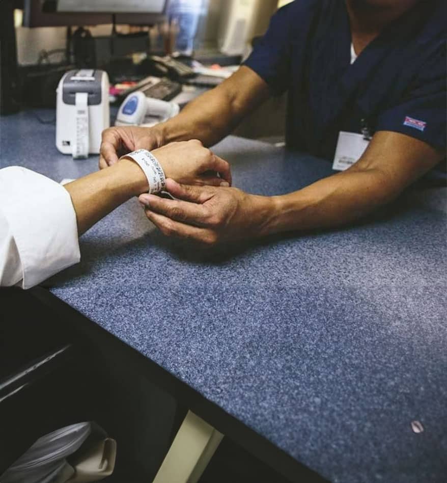 Bracelet d'identification thermique posé au poignet d'un patient. Vérification d'identité médicale.