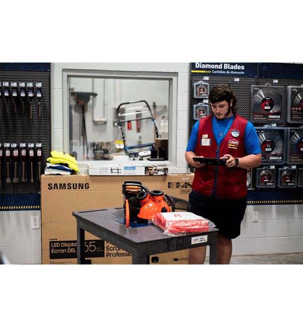 Employé de Lowe's utilisant une tablette Zebra ET40-45 devant des outils et un écran Samsung.
