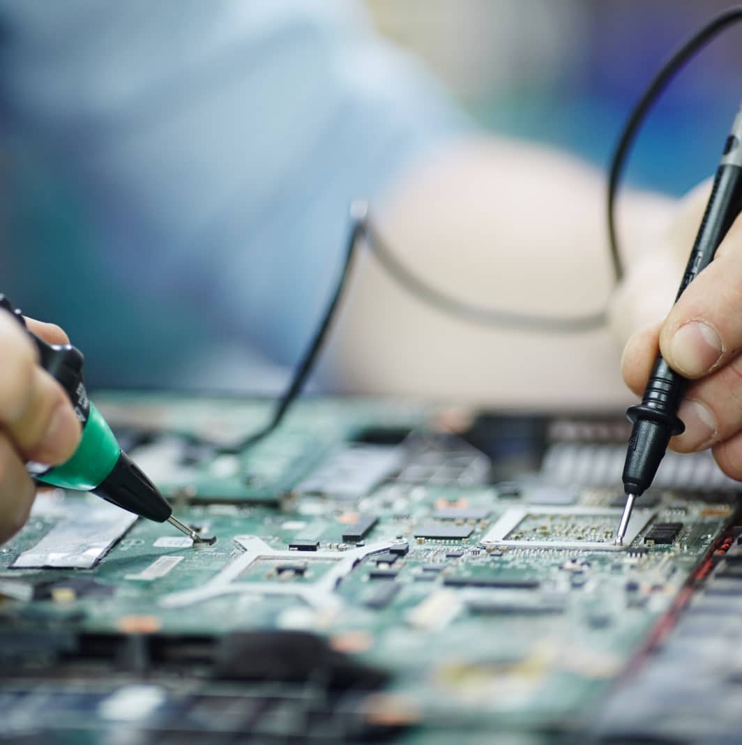 Les mains utilisant des sondes pour tester et diagnostiquer les composants d'un circuit imprimé d'ordinateur, avec une vue rapprochée du matériel électronique, supportant le pilotage et la remontée des KPI pour un suivi efficace des performances.