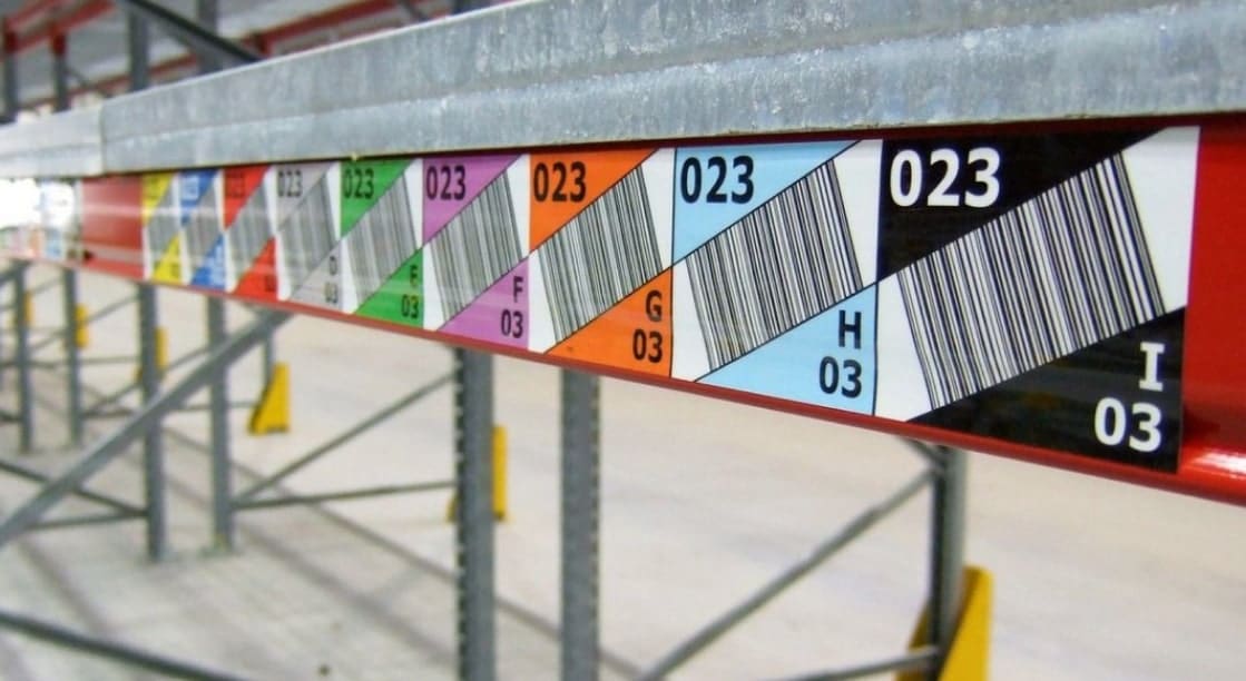 Étagères d'entrepôt étiquetées avec codes-barres et numéros. Services WIIO pour la gestion logistique.