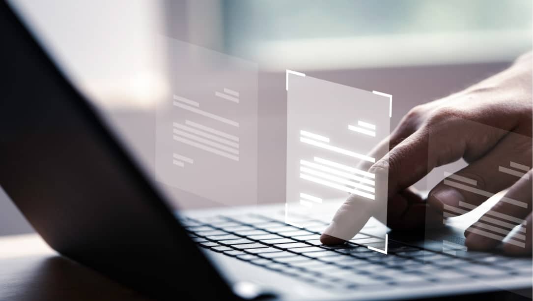 Main pointant sur un ordinateur portable avec des documents virtuels. Solutions métiers.