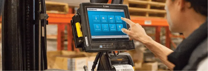 Solutions métiers : écran tactile Zebra sur chariot élévateur dans un entrepôt.